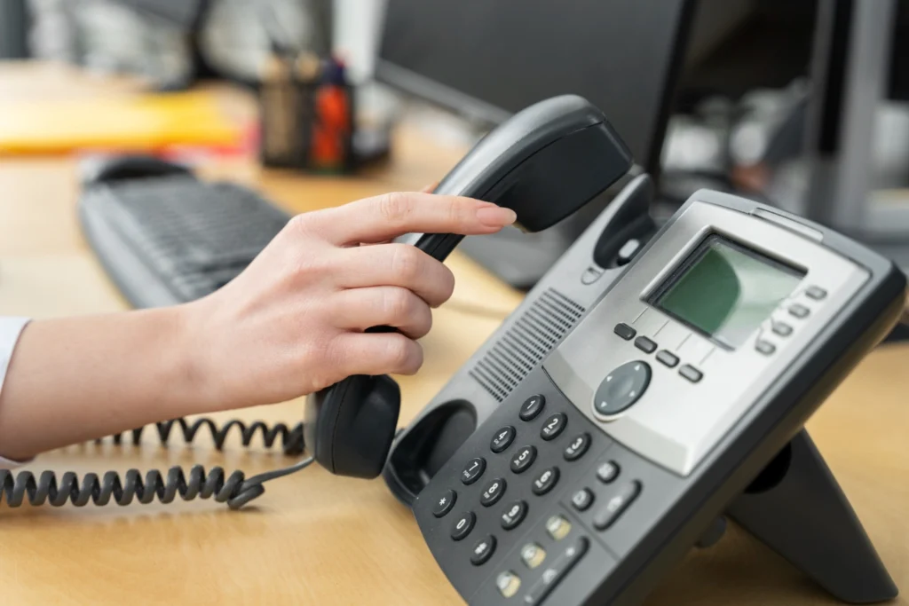 Close-up of a business VoIP phone system handset and keypad on an office desk