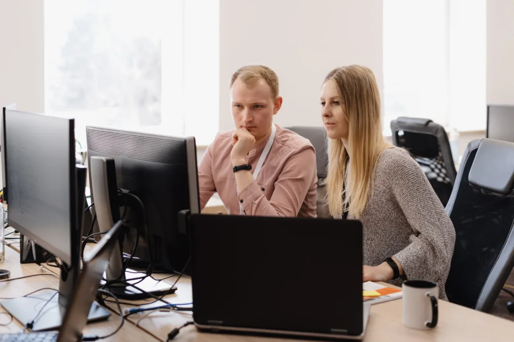 Two small business employees looking at a computer screen while managing their office IT setup